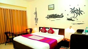 Habitación de hotel con cama, escritorio, silla, mesita de noche y pared decorada.