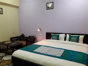 Une chambre d’hôtel avec un lit, un petit bureau et une chaise.