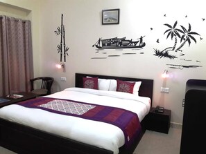 Une chambre d’hôtel comprenant un lit, une table de chevet, une chaise et des œuvres d’art décoratives sur les murs.