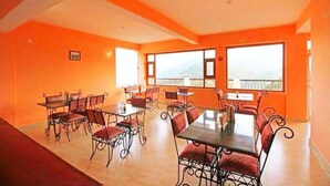 Un espace repas avec des tables et des chaises, de grandes fenêtres et une vue sur l’extérieur.