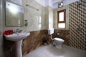 A bathroom with a sink, mirror, toilet, and a patterned wall. - Hotel Avlokan (Nainital)