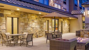 An outdoor patio with stone walls, tables, chairs, a fire pit, and an umbrella. - Best Western Plus Heber Valley Hotel (Heber City)