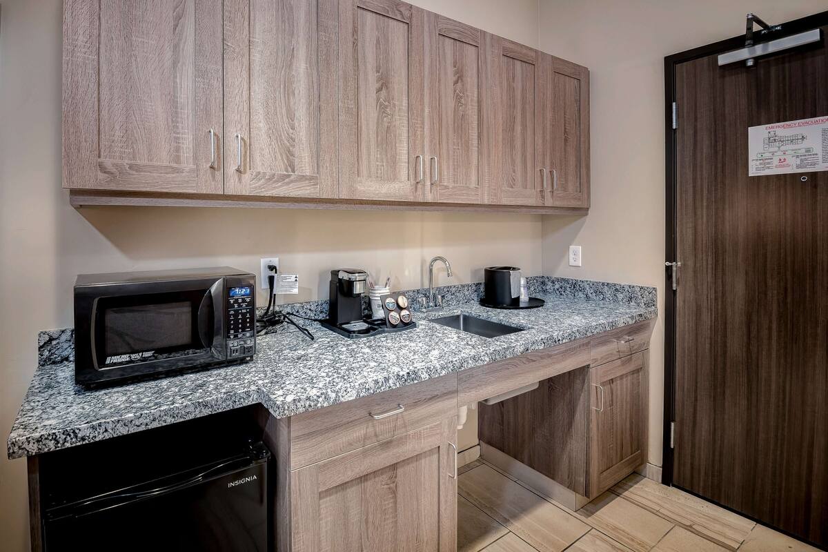 A kitchen with a microwave, coffee maker, and sink.