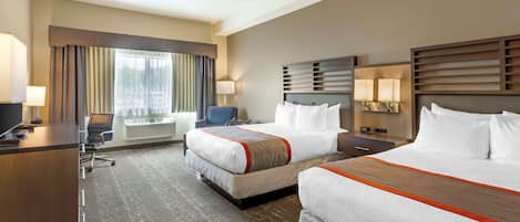 A hotel room with two beds, a desk, a chair, and a large window with curtains.