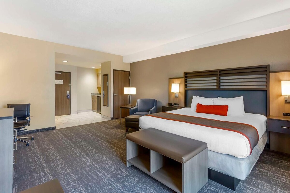 A hotel room with a large bed, bedside tables, a desk, and a chair.