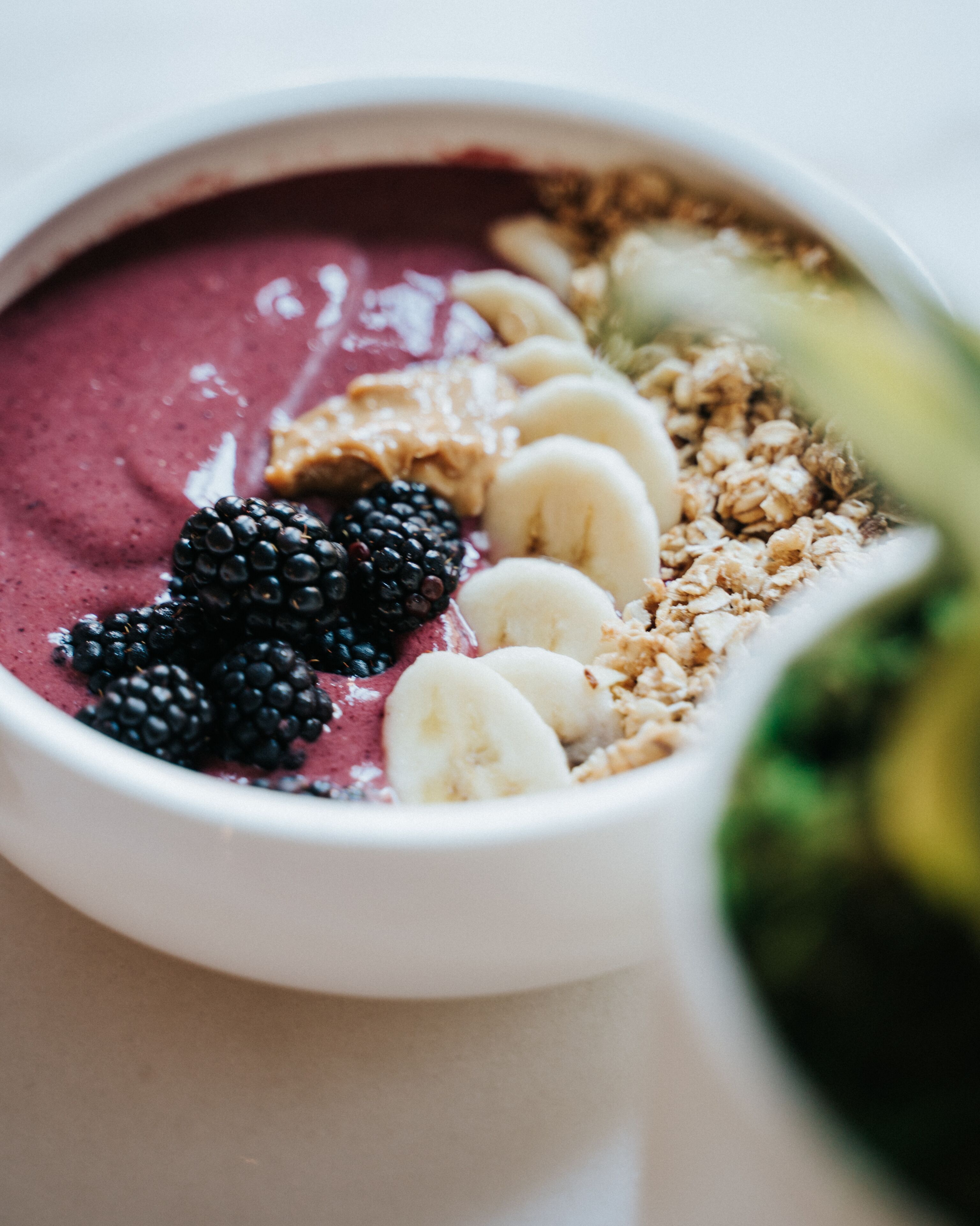 A bowl of smoothie with blackberries, bananas, and granola.