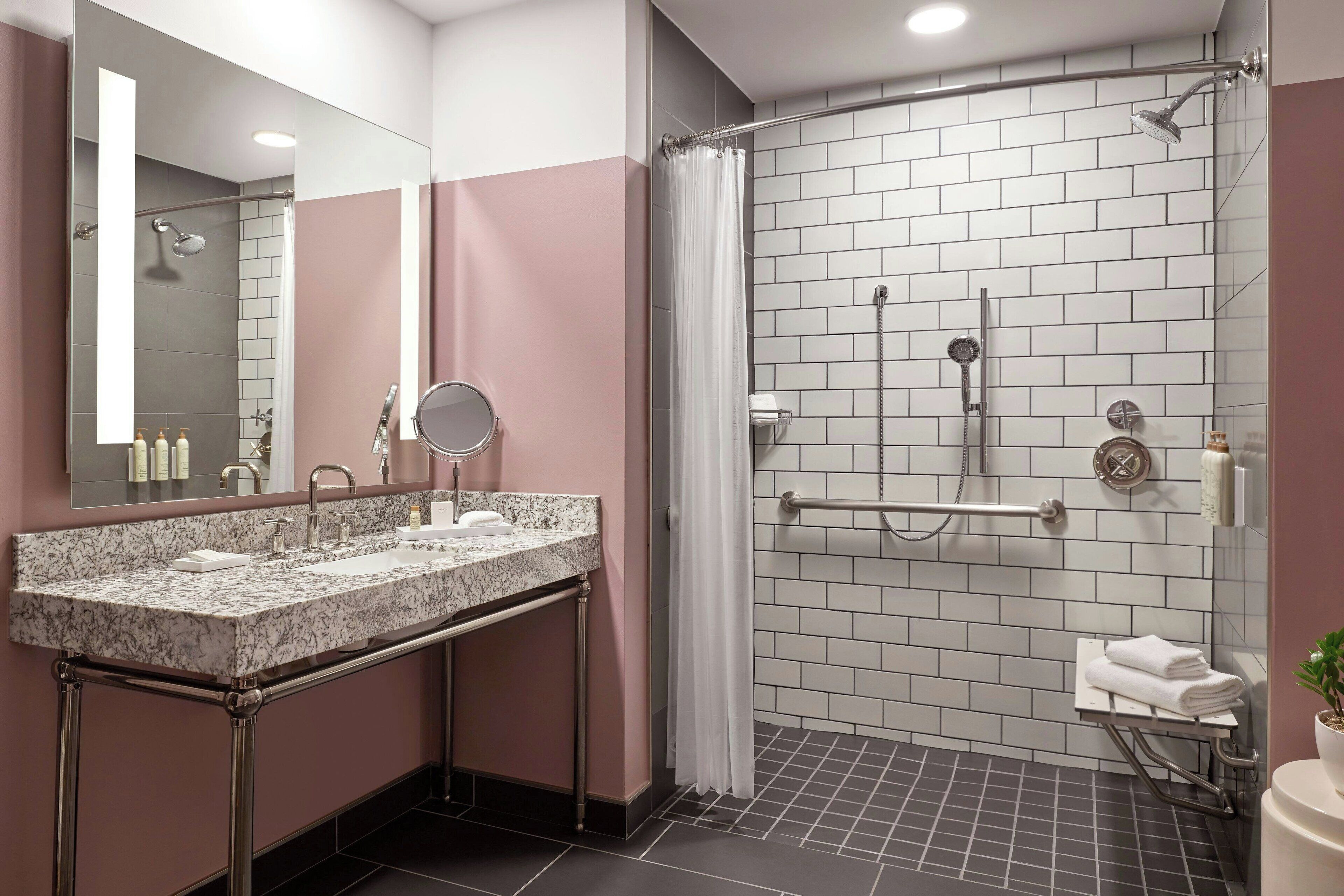 Un baño moderno con un lavamanos de mármol, un espejo grande, una ducha con puerta de vidrio y un toallero pequeño.