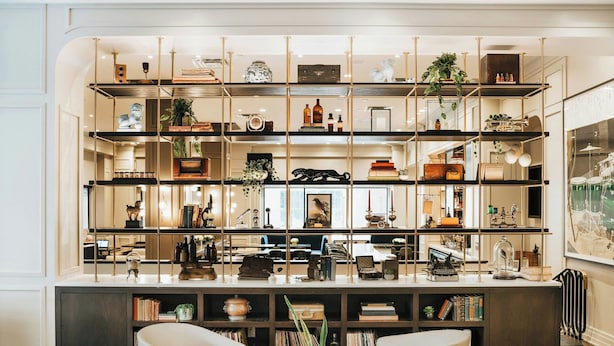 Een moderne woonkamer met een grote boekenkast, twee fauteuils en een salontafel.