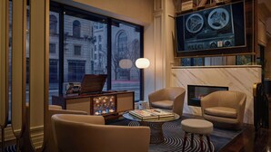 Een moderne hotellobby met een groot raam, comfortabele zitplaatsen, een flatscreen televisie en een open haard.
