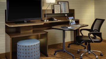 Habitación de hotel con televisión de pantalla plana, un escritorio con una computadora portátil, un teléfono y una silla.