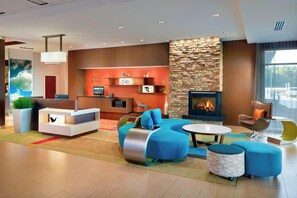 A modern hotel lobby with a reception desk, seating area, fireplace, and a stone accent wall. - Fairfield Inn & Suites by Marriott Hendersonville Flat Rock (Flat Rock)