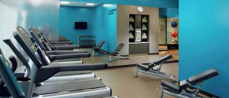 Un gimnasio con cintas de correr, mancuernas y equipamiento de ejercicio.
