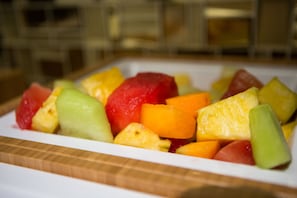 Une assiette blanche contenant divers fruits, notamment de la pastèque, du melon et de l’ananas.