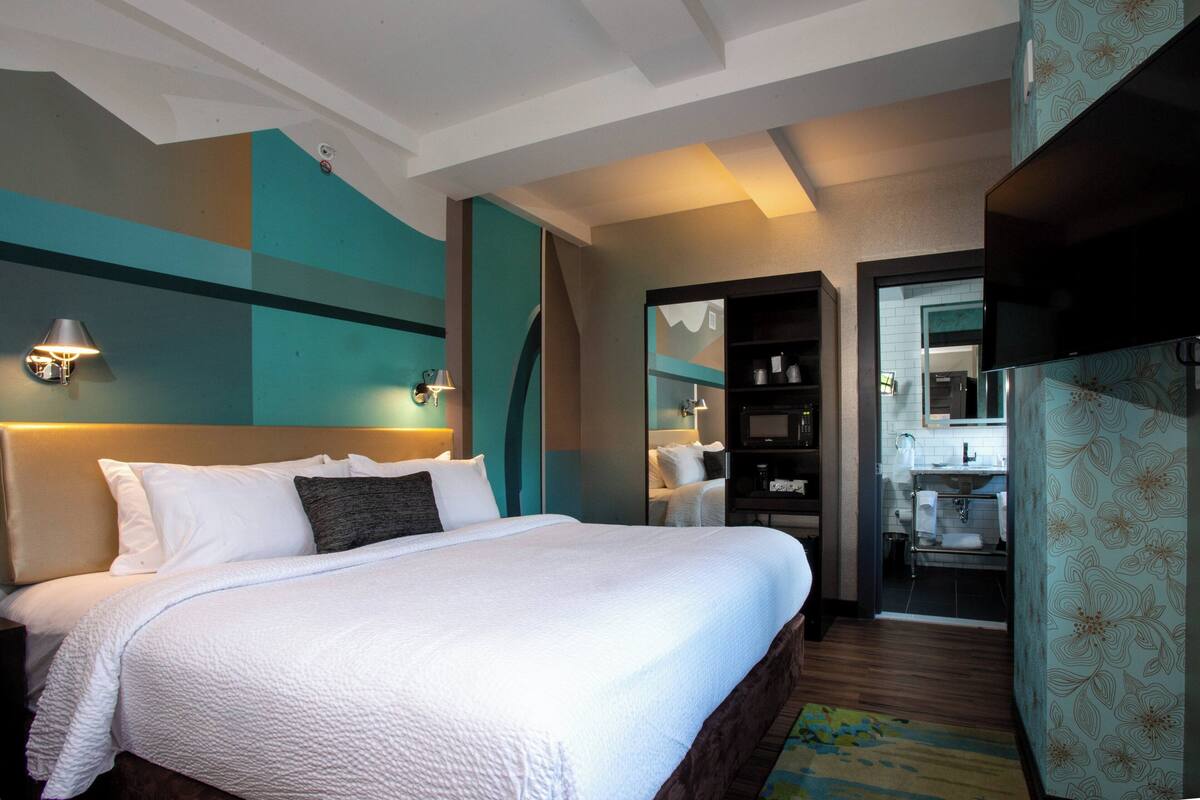 Ein Hotelzimmer mit einem großen Bett, einem Kleiderschrank, einem Badezimmer und einer Küchenzeile.