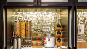 A kitchen counter with a coffee machine, a container of oatmeal, and a display of jars. - Fairfield Inn & Suites by Marriott Philadelphia Downtown/Center City (Philadelphia)