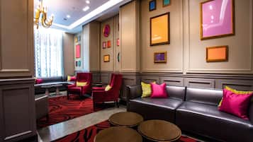 A modern lobby with a black leather sofa, red chairs, and a red carpet.