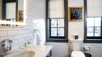Et moderne badeværelse med en marmorvask, toilet og et vindue med skodder.