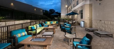 An outdoor patio area with seating arrangements, tables, and umbrellas.