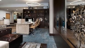 Un espace de bureau moderne comprenant un comptoir d’accueil, des chaises de bureau, un ordinateur et des éléments de décoration.