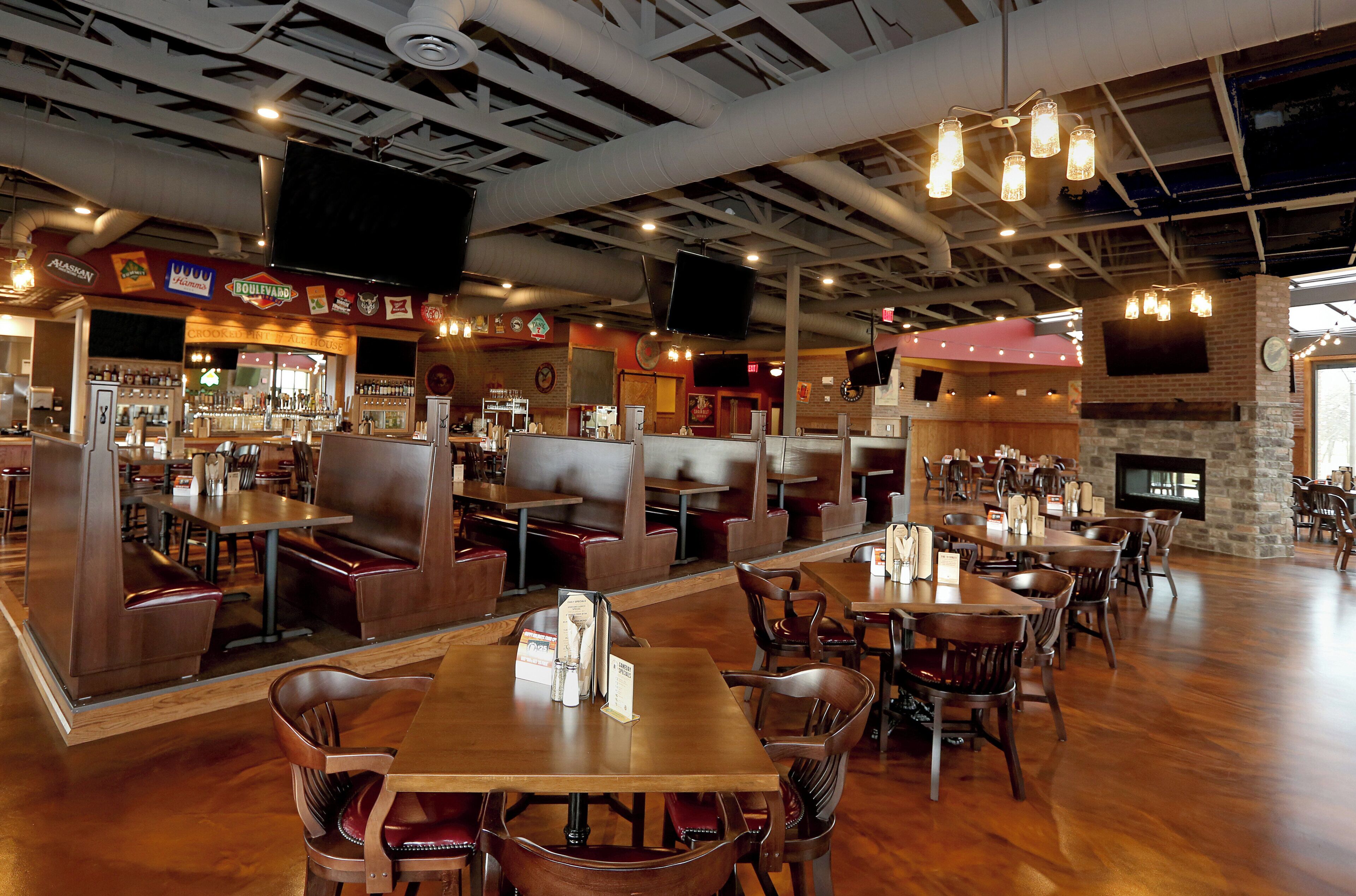 Un interior de restaurante con cabinas, mesas y una zona de bar.