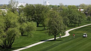 Un parcours de golf avec un chemin bien défini, des arbres et un chariot de golf.