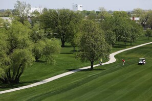 Een golfbaan met een duidelijke route, bomen en een golfkar.