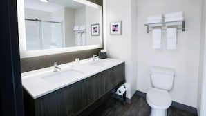 Une salle de bain moderne avec un double vasque, des toilettes et un grand miroir.