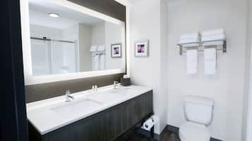 A modern bathroom with a double sink, a toilet, and a large mirror.