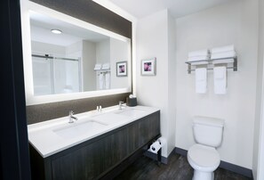 Une salle de bain moderne avec un double vasque, des toilettes et un grand miroir.