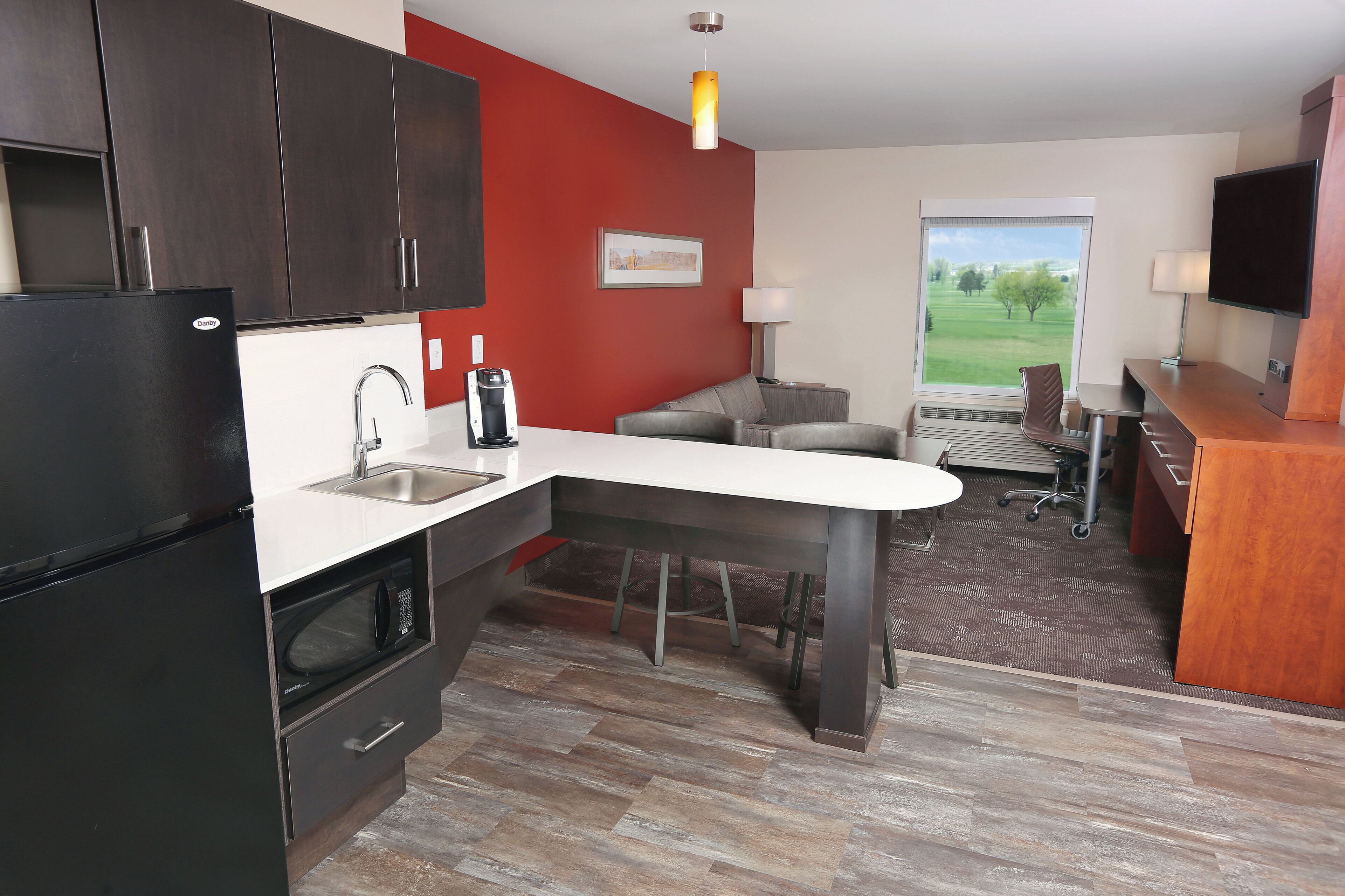 Una cocina compacta con horno integrado, cafetera y lavamanos.