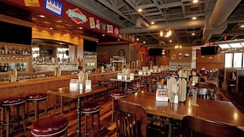 A bar area with multiple stools, a counter with various bottles, and signs for different beers.