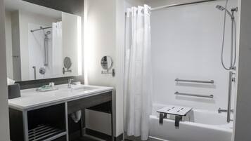 A modern bathroom with a white sink, mirror, and shower area.