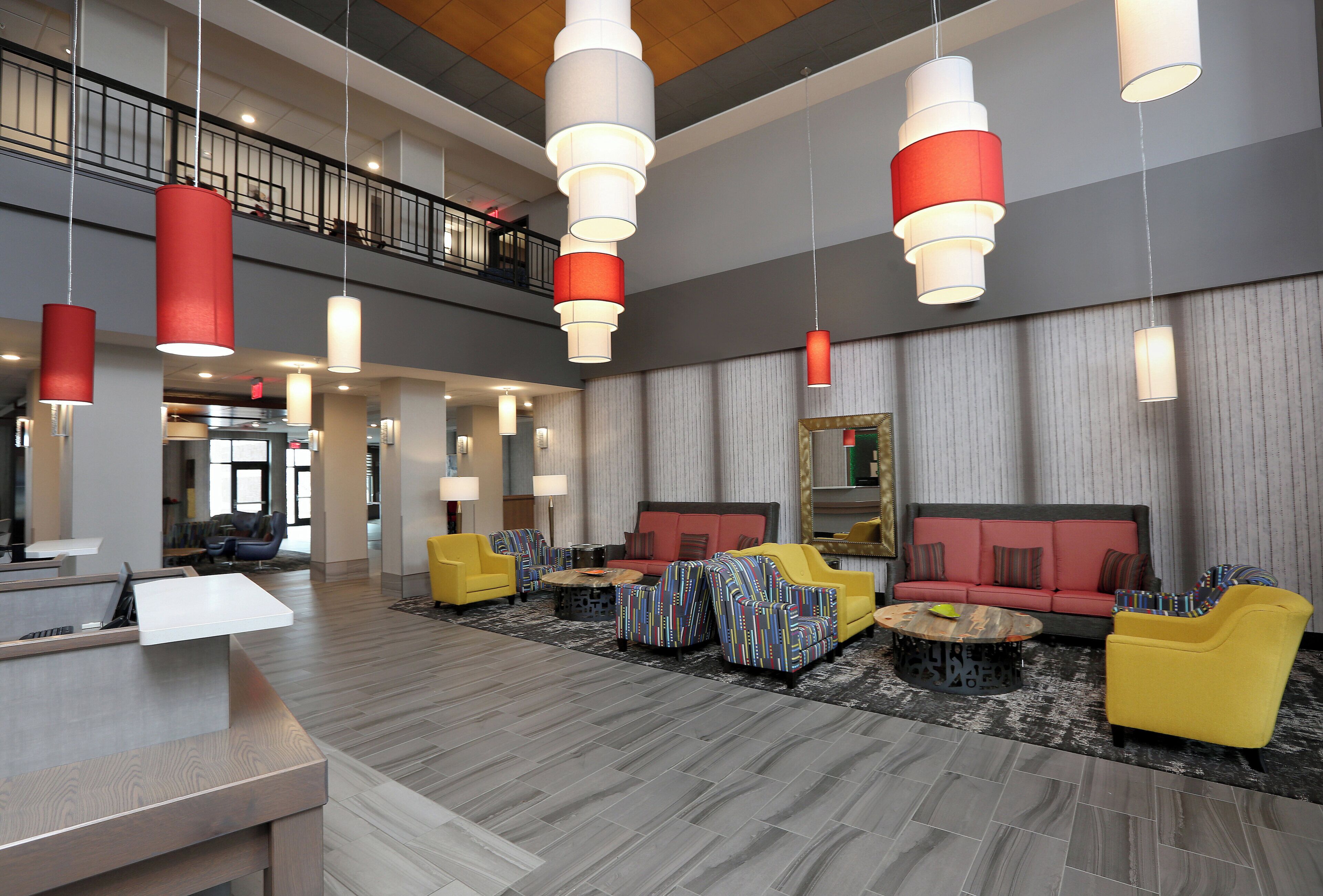A spacious lobby with multiple seating areas, a reception desk, and a staircase leading to an upper level.