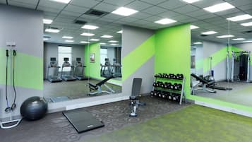 A gym with treadmills, a bench press, and a rack of dumbbells.