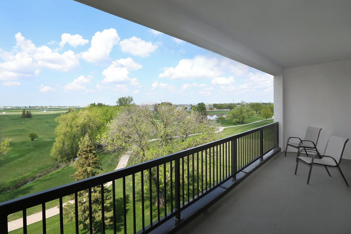 Un balcon donnant sur un paysage verdoyant et des arbres.