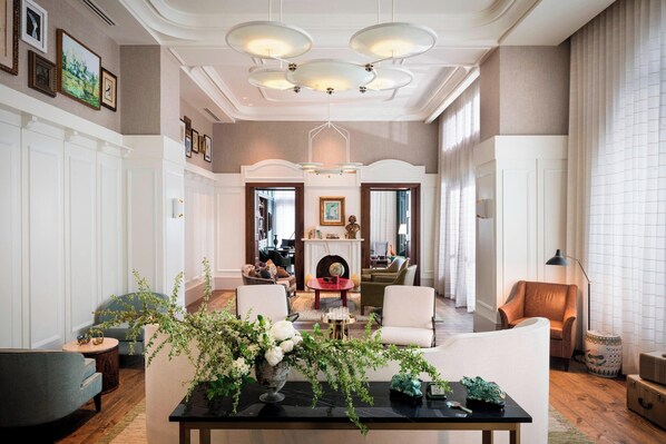 A spacious living room with a fireplace, comfortable seating, and a modern chandelier.