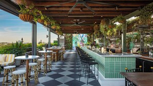 A bar area with a checkered floor, bar stools, and hanging plants. - Perry Lane Hotel, A Luxury Collection Hotel, Savannah (Savannah)