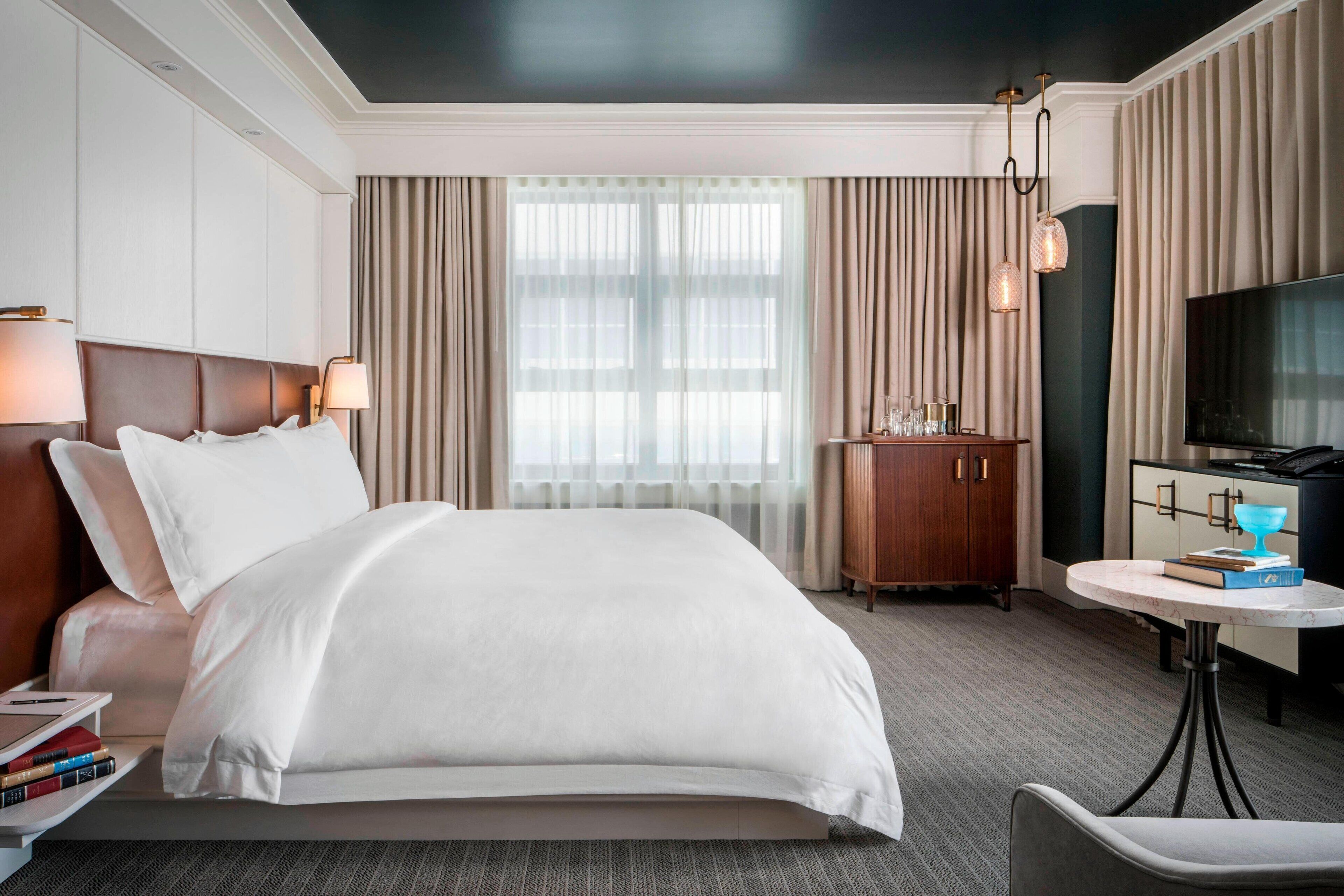 A hotel room with a large bed, a desk with a TV, and a wardrobe.