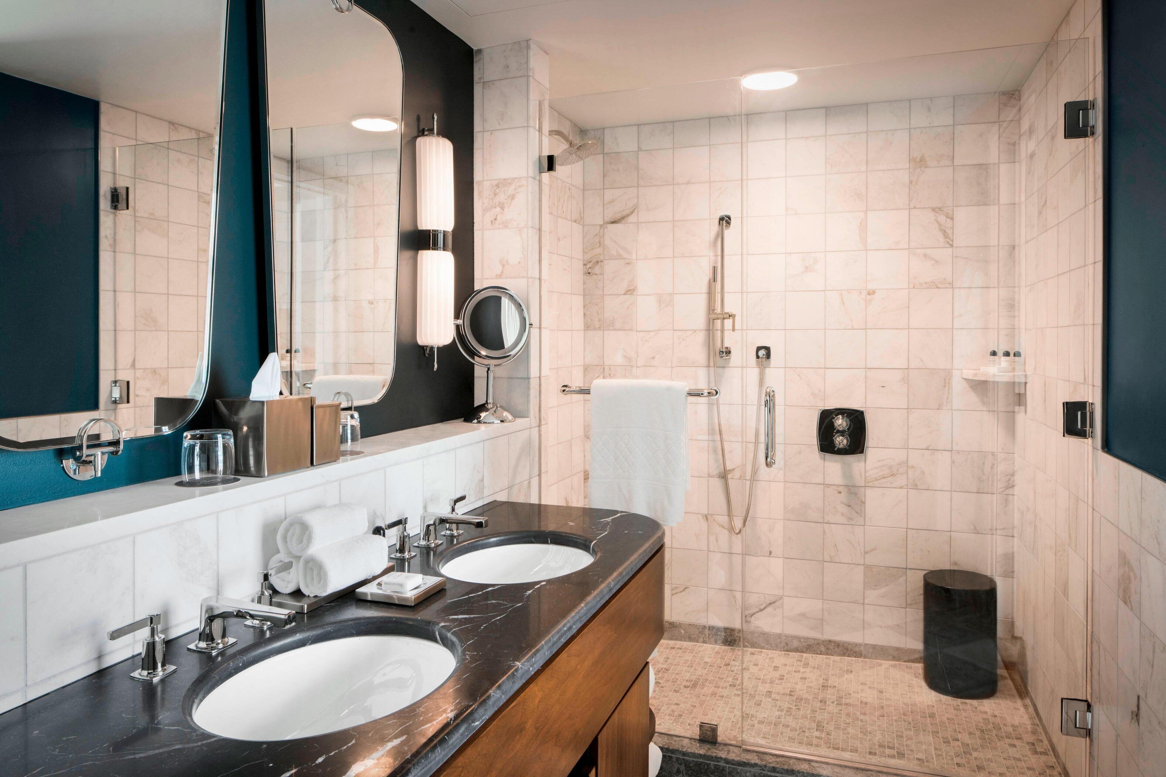 Un baño moderno con dos lavamanos, un espejo grande y una ducha a ras de suelo.