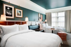 A hotel room with a large bed, a sofa, a small table, and a window with curtains.