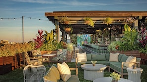 An outdoor patio with a wooden pergola, green and white cushioned seating, and hanging planters. - Perry Lane Hotel, A Luxury Collection Hotel, Savannah (Savannah)