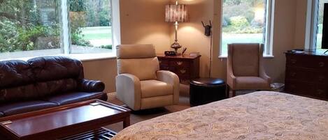 A bedroom with a large bed, two armchairs, a sofa, and a small table.