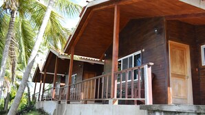 A wooden house with a porch, surrounded by palm trees. - Hotel Santa Bárbara Tikal (San Benito)
