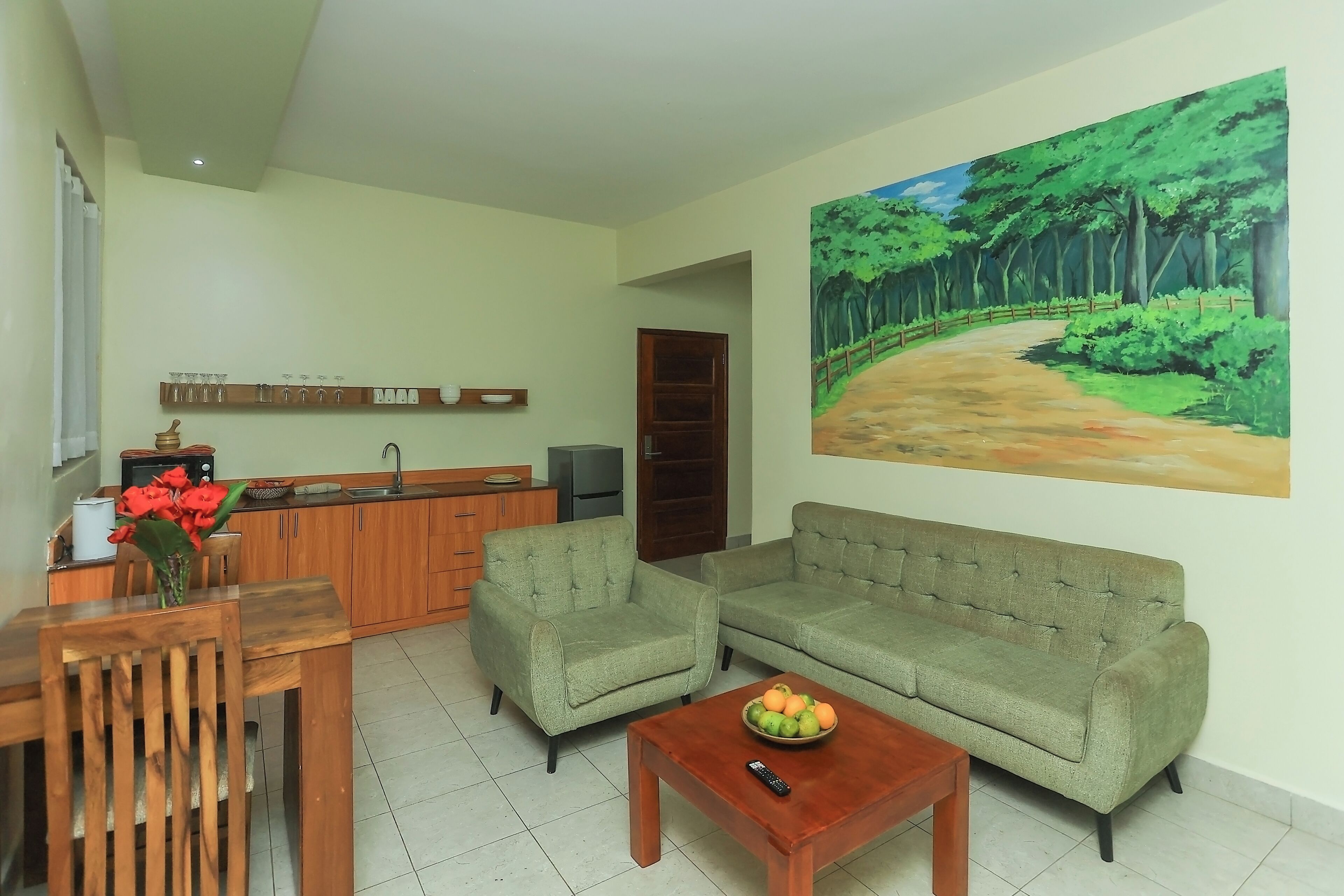 Una sala de estar con un sofá, una mesa de centro y un cuadro de un sendero en el bosque.