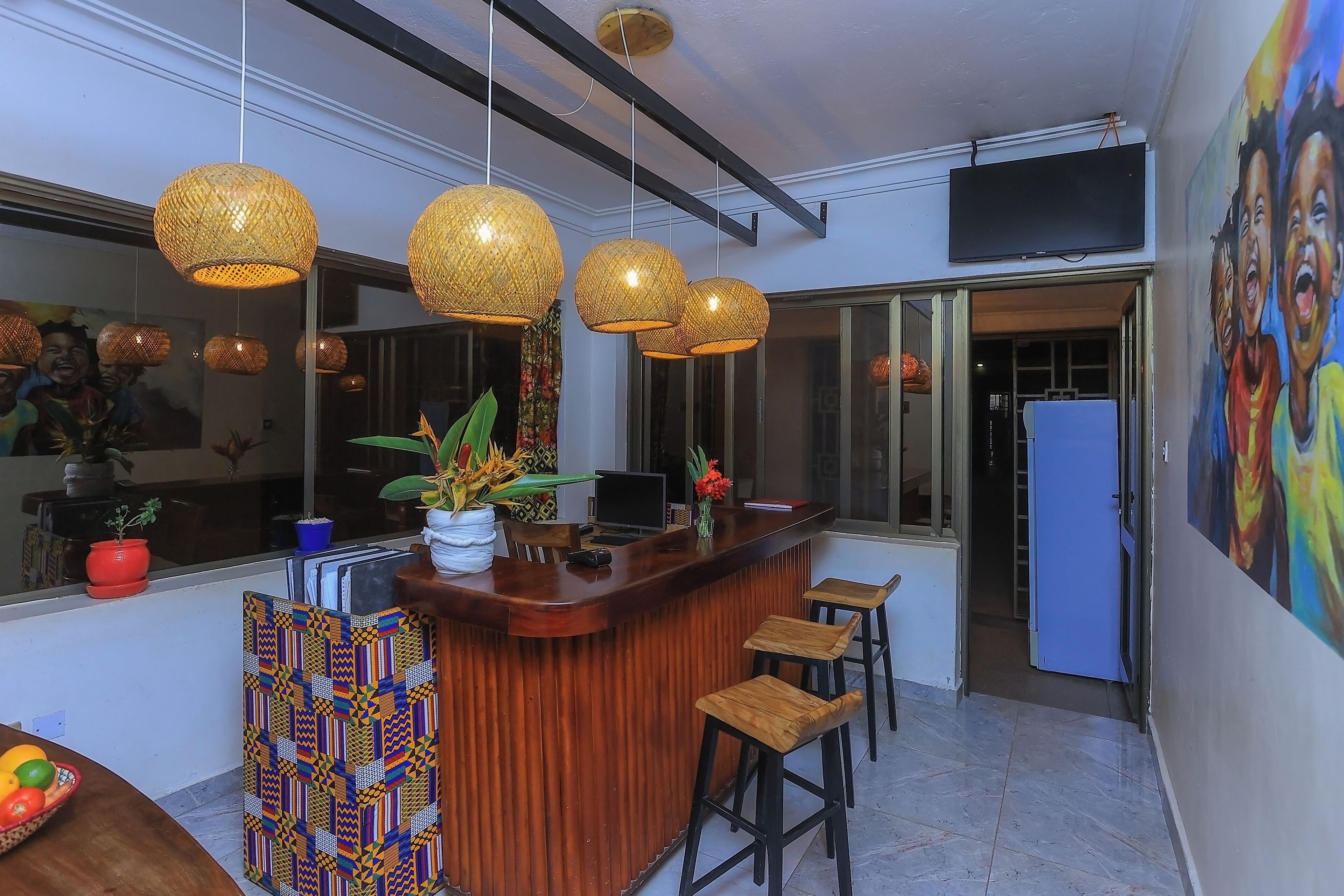 A modern kitchen with a wooden bar, hanging wicker pendant lights, and a large window.