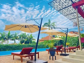 Una piscina al aire libre, sombrillas, sillones reclinables de piscina