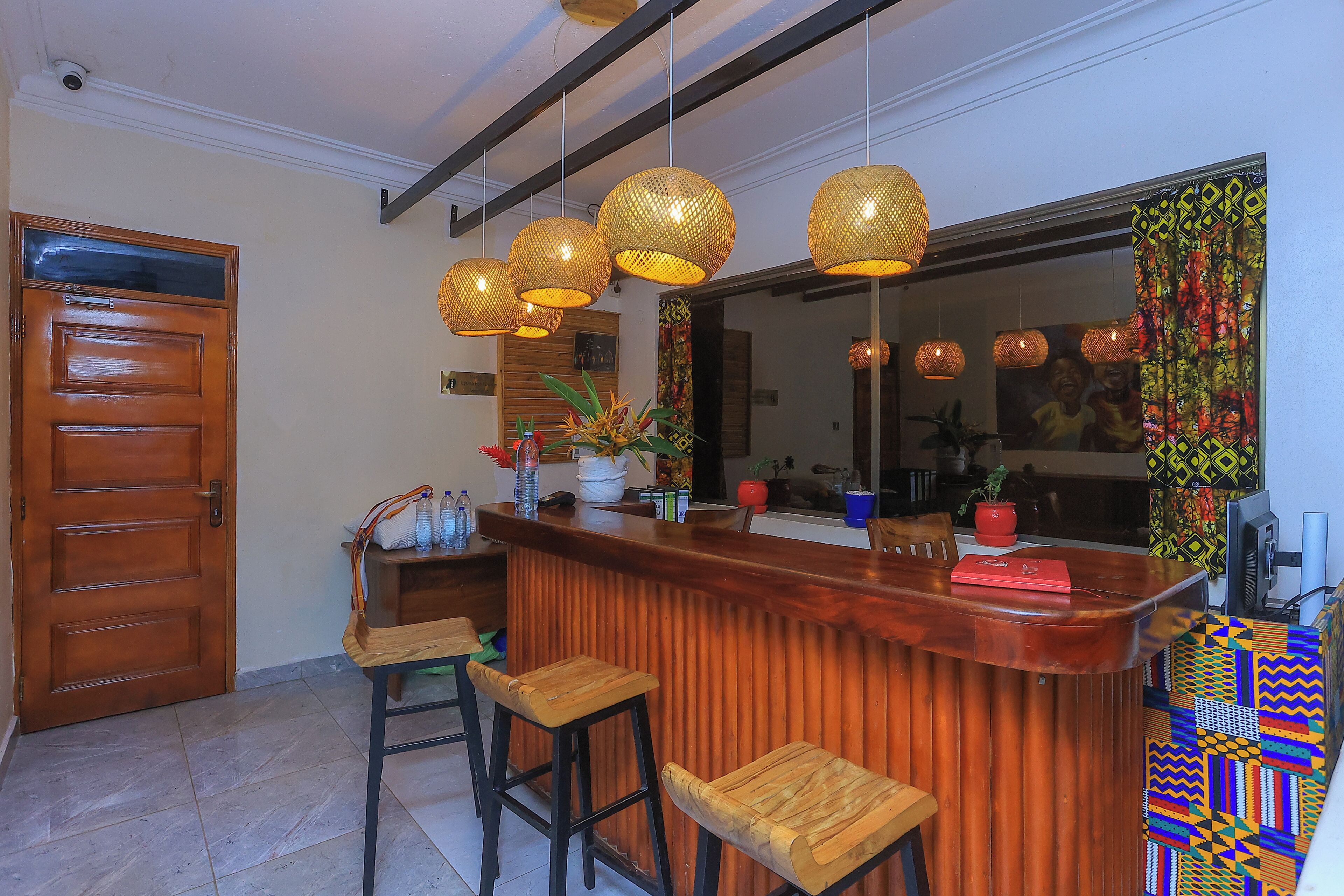 A bar area with a wooden counter, three wicker pendant lights, and two wooden stools.