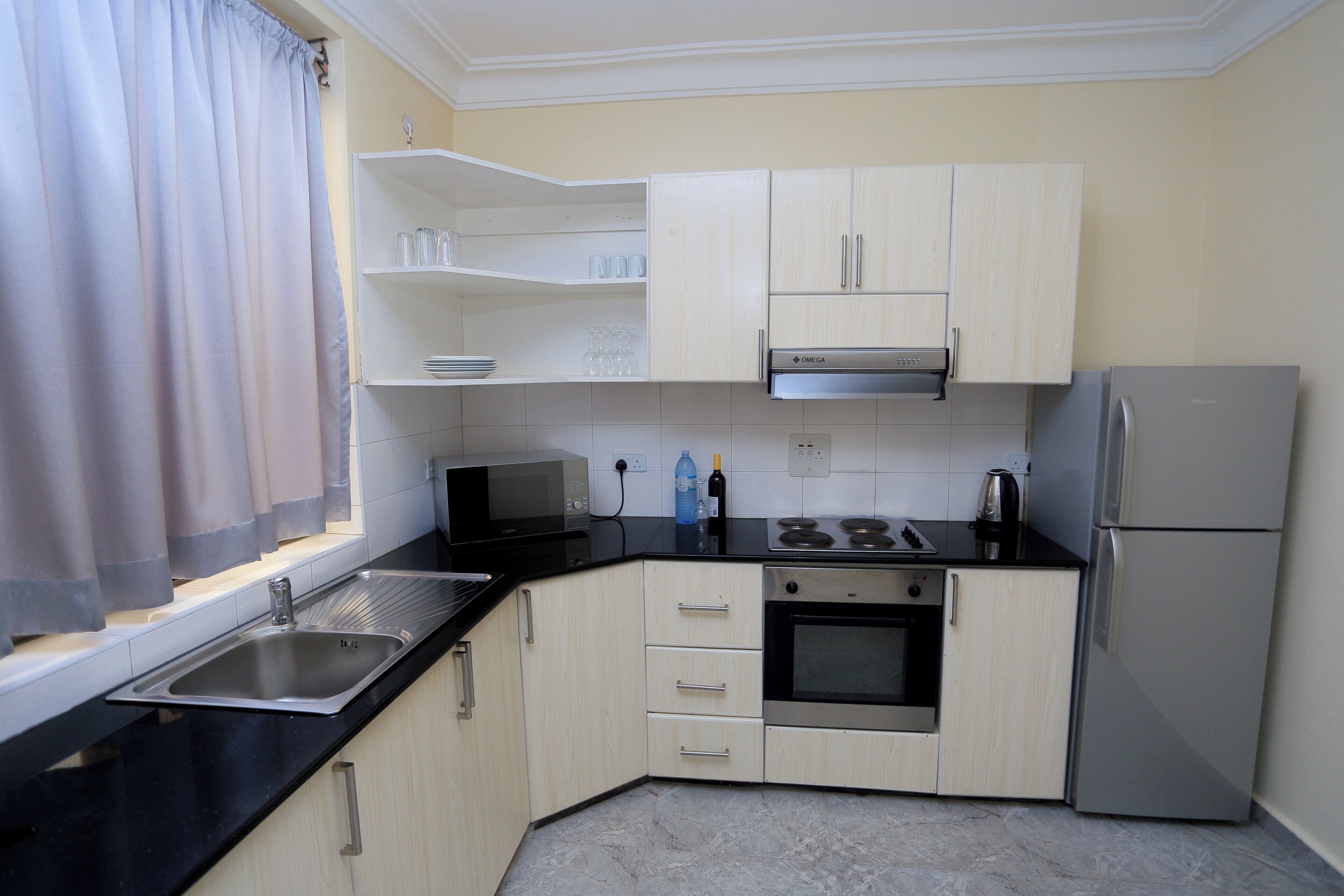 A compact kitchen with a microwave, oven, and refrigerator. It includes a sink and a countertop with cabinets.