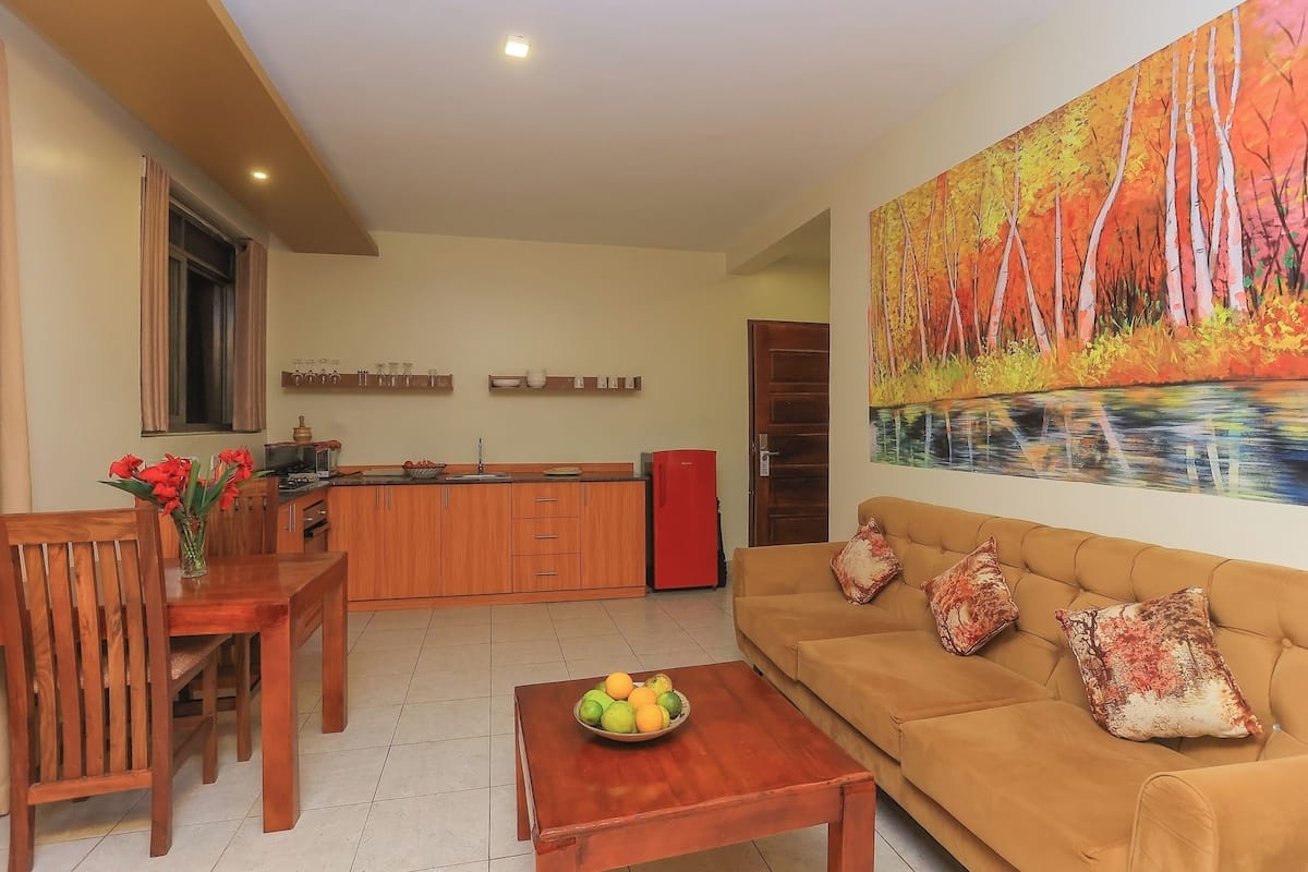 Un salon avec un canapĂ©, une table basse et un tableau reprĂ©sentant une forĂȘt.