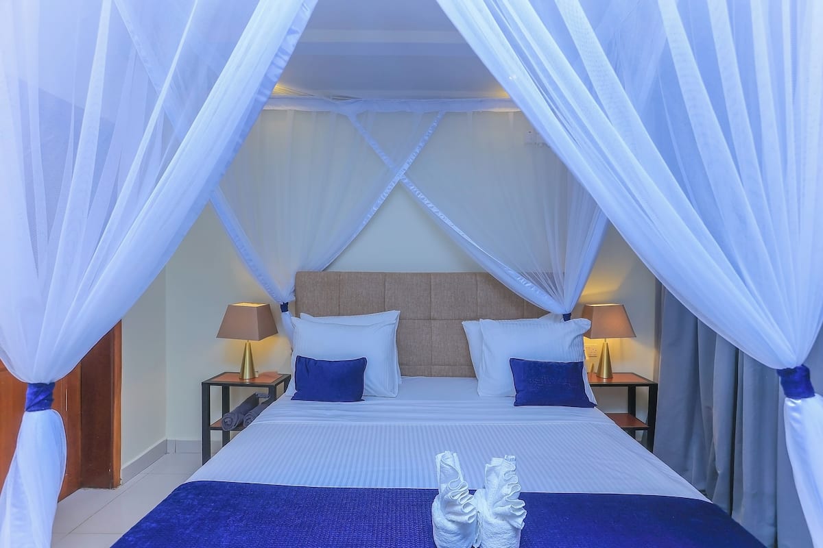 Une chambre dâhĂŽtel avec un lit, deux tables de chevet, des lampes et un lit Ă baldaquin.